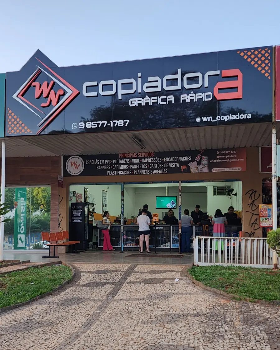 Fachada da WN Copiadora em Sobradinho, com o letreiro Copiadora Gráfica Rápida e clientes sendo atendidos no balcão